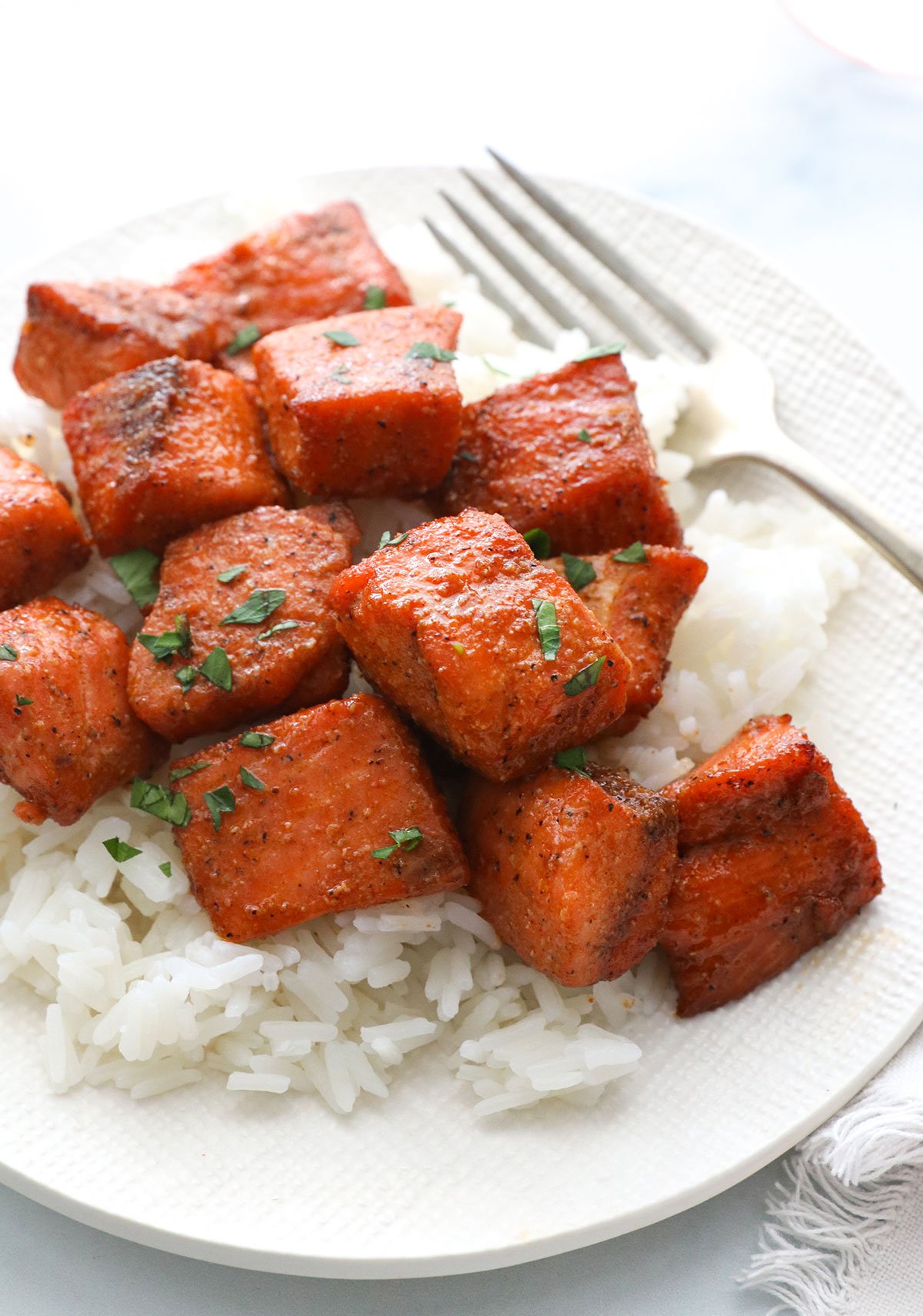 air fryer salmon bites served on a bed of rice with a fork.