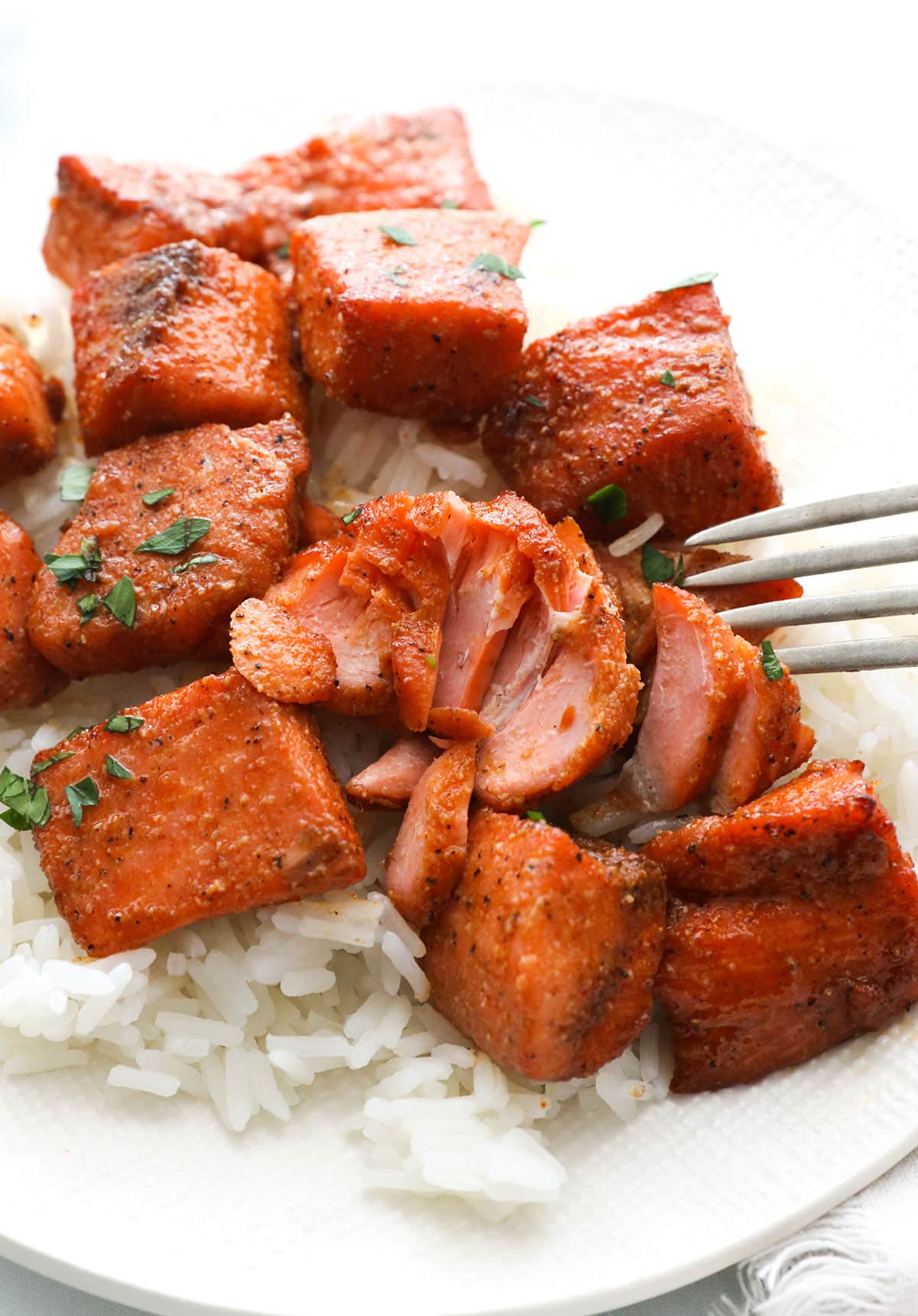 air fryer salmon bites flaked with a fork on a bed of rice.