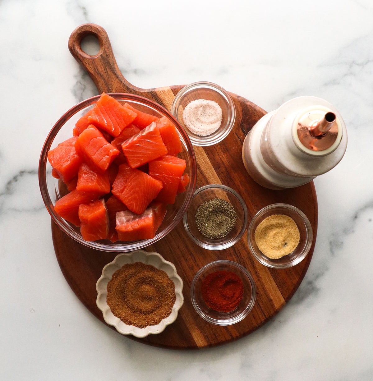 salmon and spices arranged on a cutting board in separate bowls.