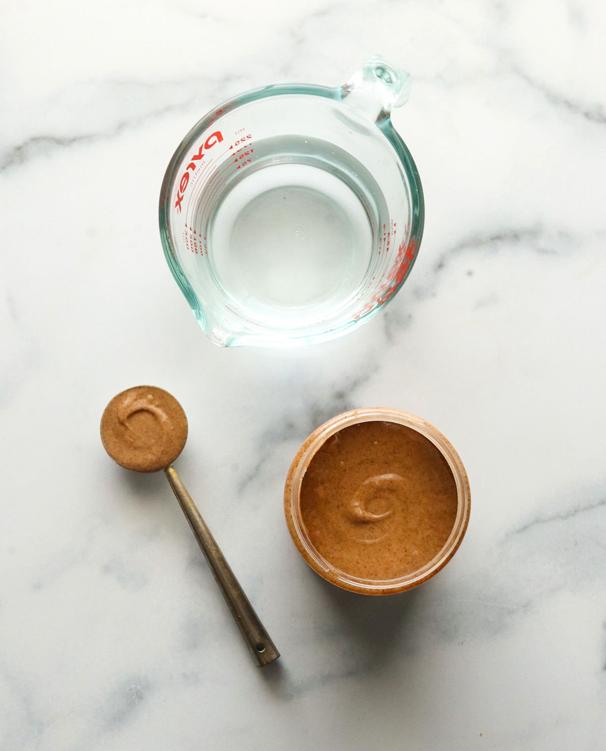 almond butter and water sitting on a marble surface.