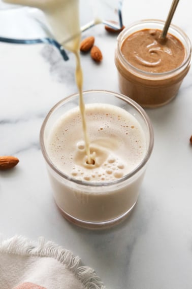 almond milk poured into a glass from a blender.