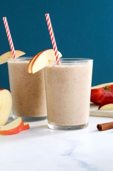 two glasses of apple smoothie with blue background