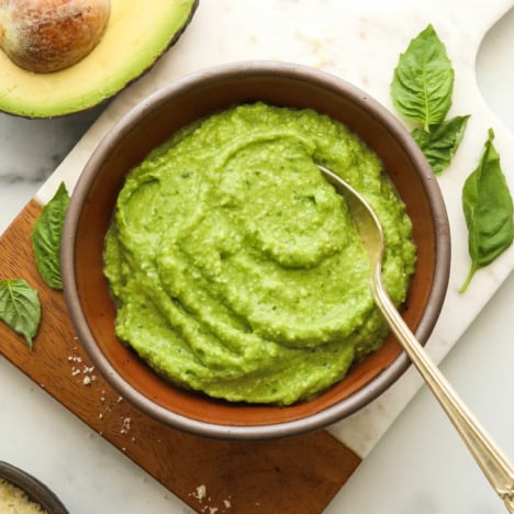 avocado pesto in a brown bowl with a spoon.