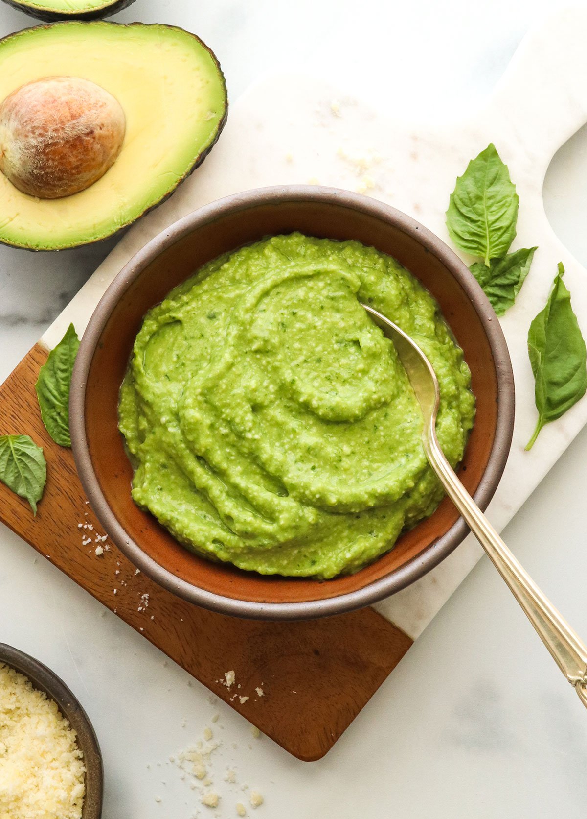 avocado pesto in a brown bowl with a spoon.