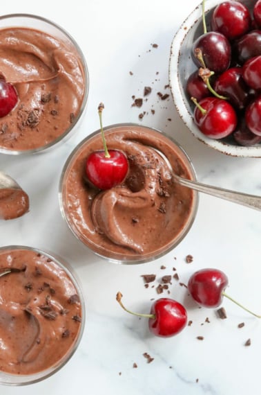 3 cups of chocolate pudding with cherries on top