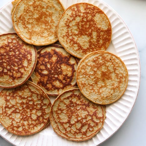 banana oatmeal pancakes layered on a white plate.