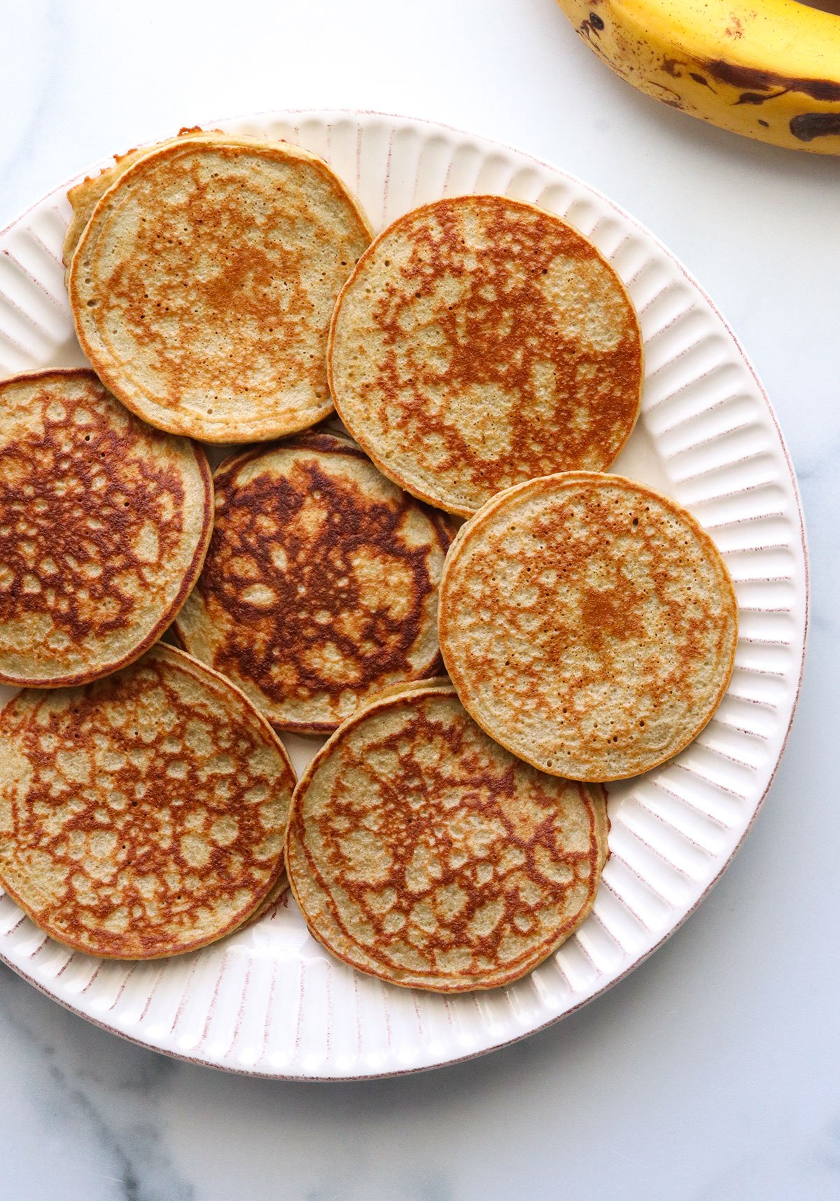 banana oatmeal pancakes layered on a white plate.