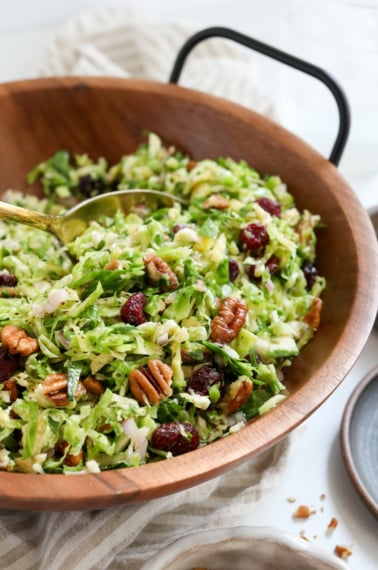 brussels sprouts salad served in wooden bowl with gold spoon