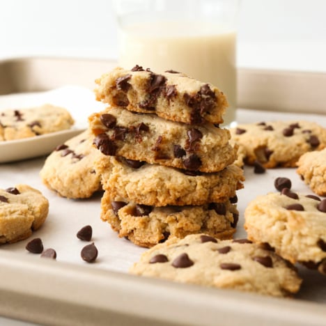 Paleo chocolate chip cookies stacked on a baking sheet.