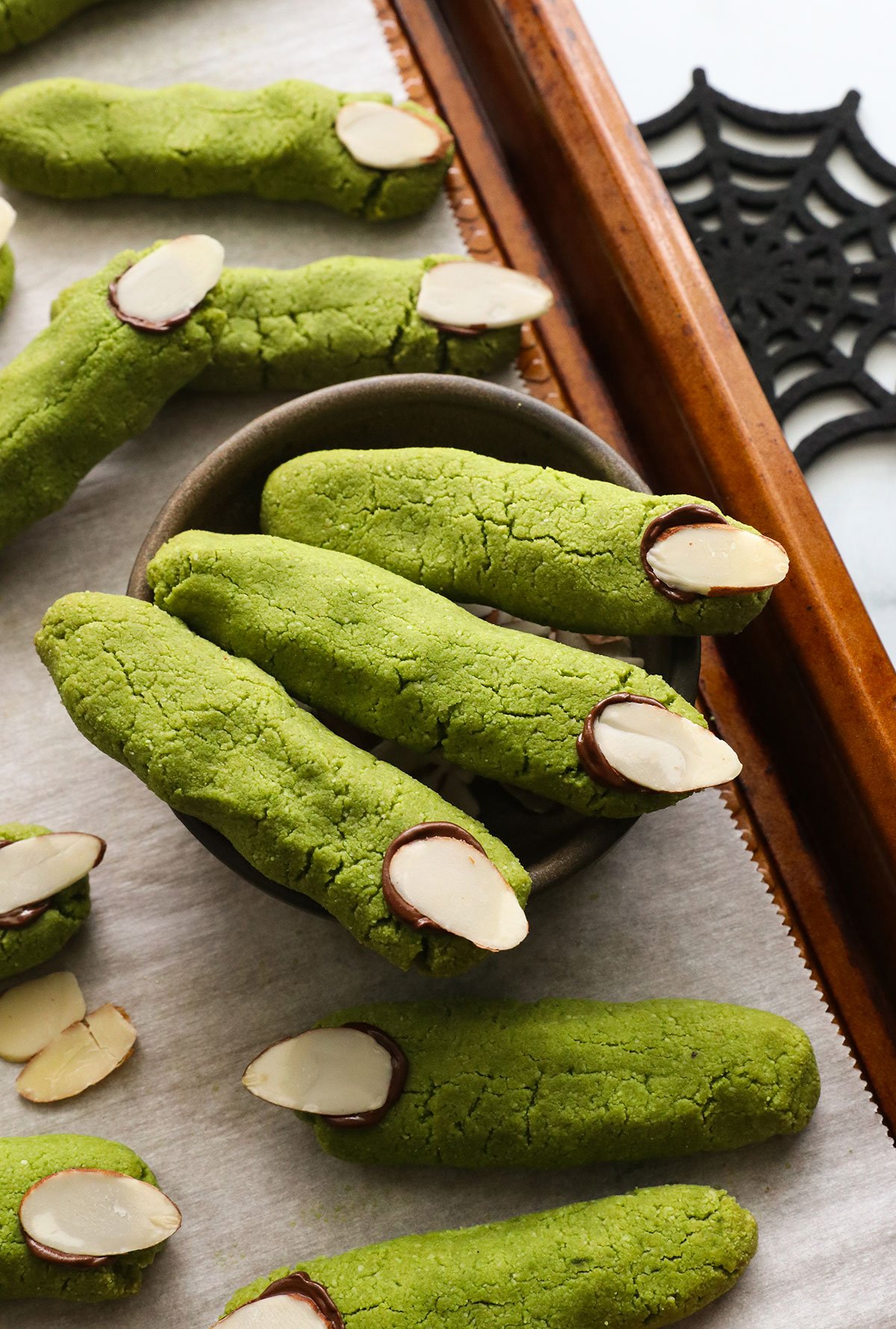 three green witch finger cookies in a bowl.