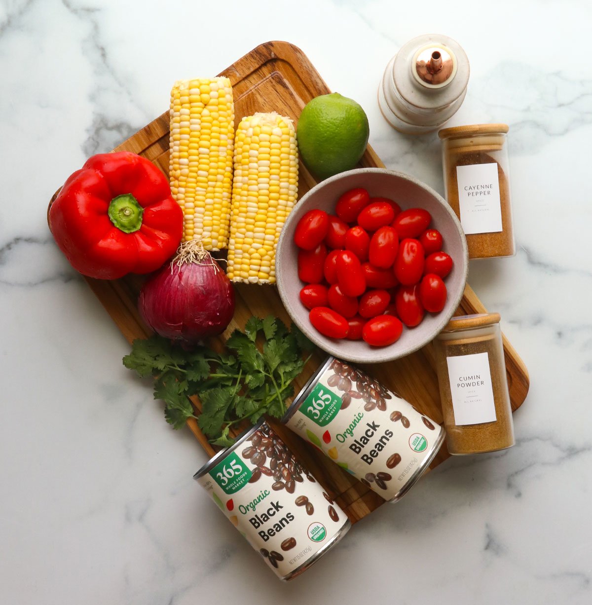 ingredients for black bean salad arranged on a cutting board. 