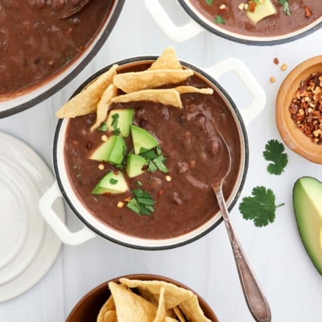 black bean soup with spoon and toppings.