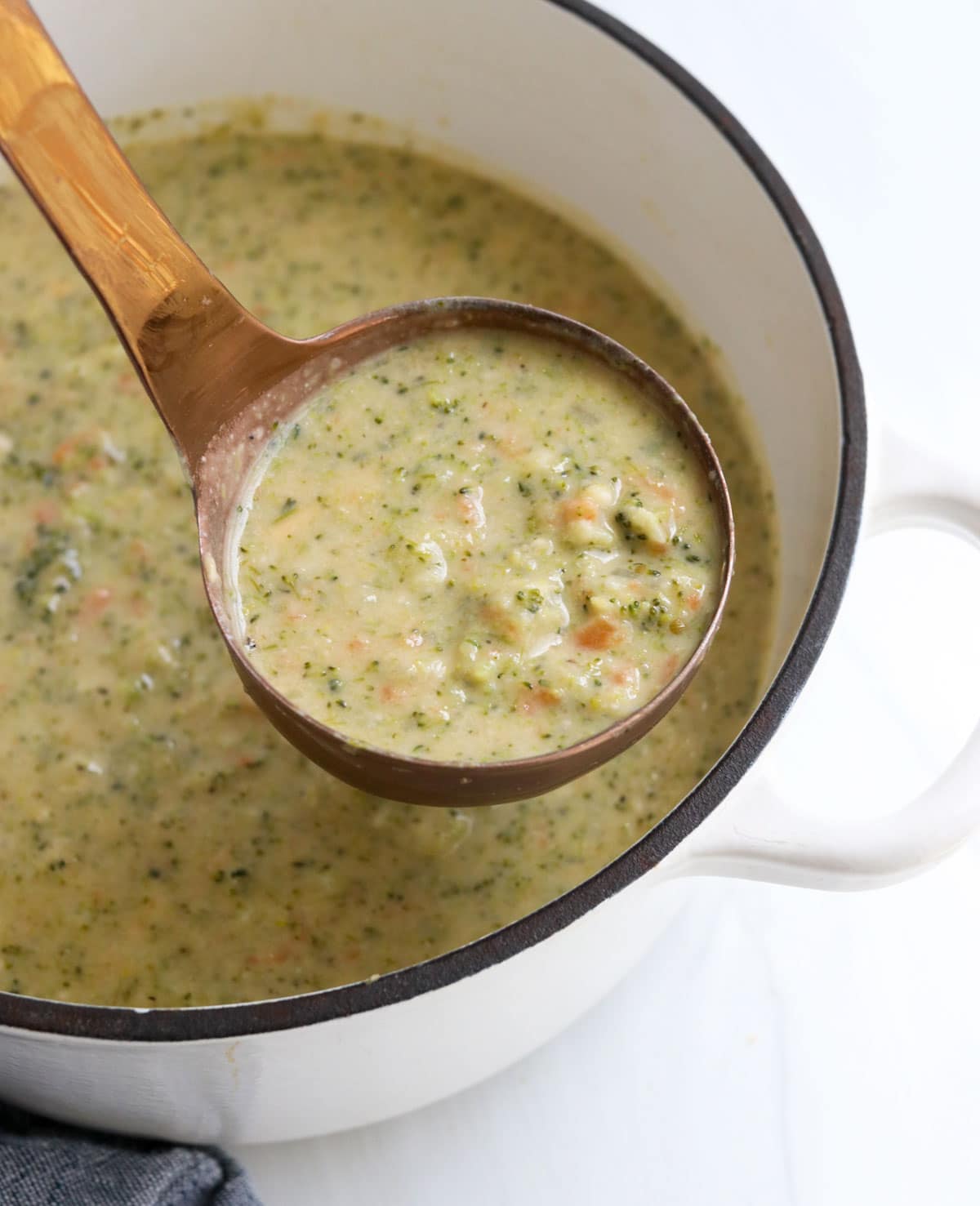 broccoli cheddar soup lifted up on ladle.