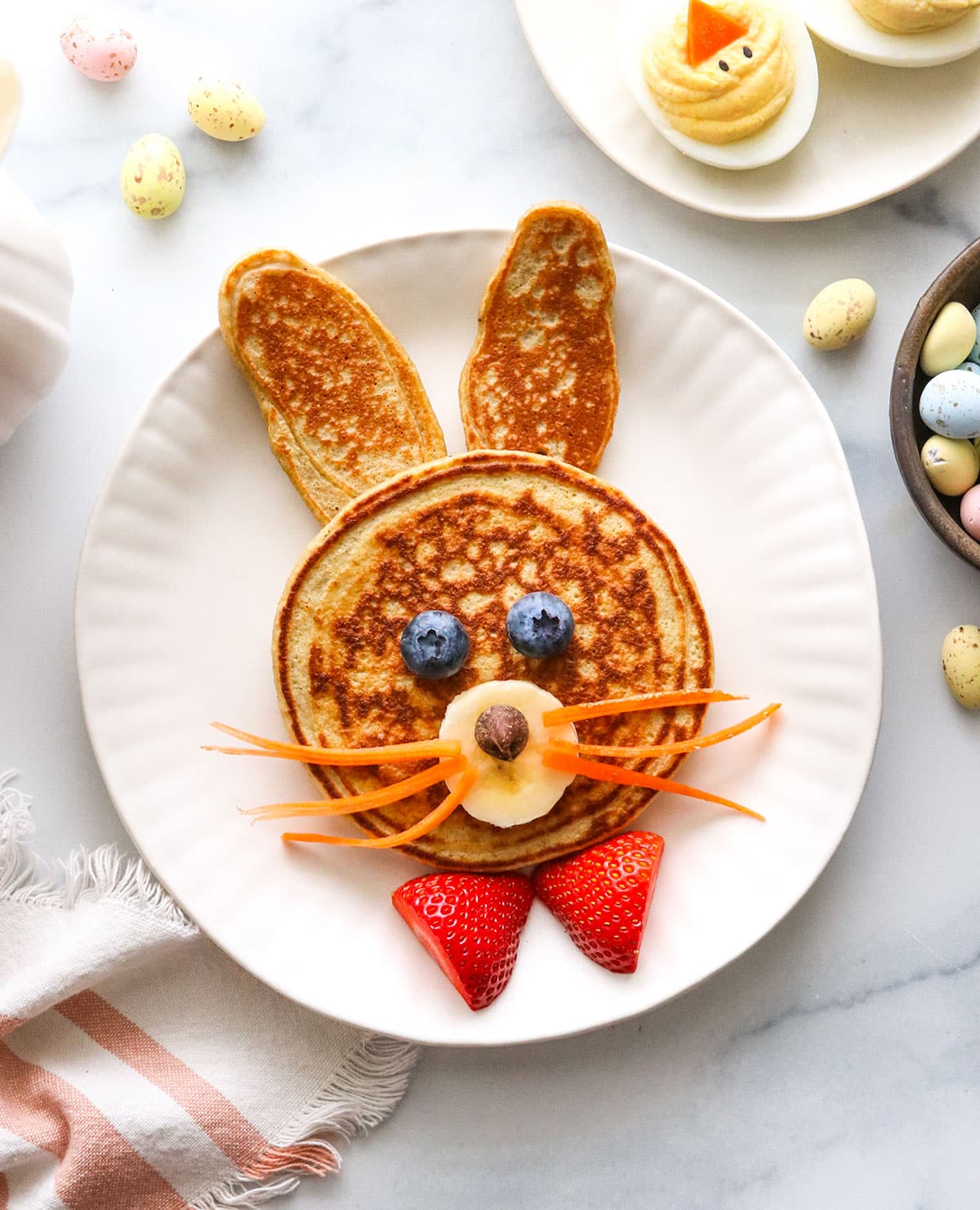 Pancakes decorated like a bunny with carrot whiskers.