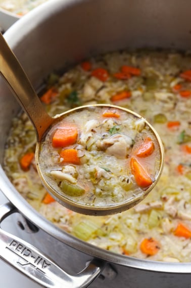 chicken and rice soup lifted up on a gold ladle.