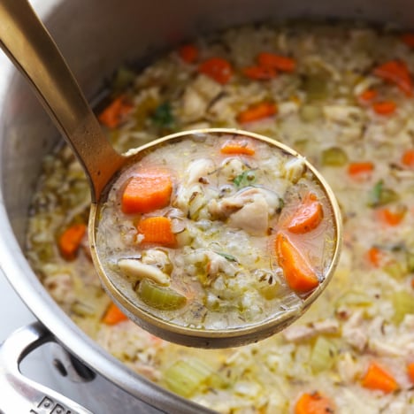 chicken and rice soup lifted up on a gold ladle.