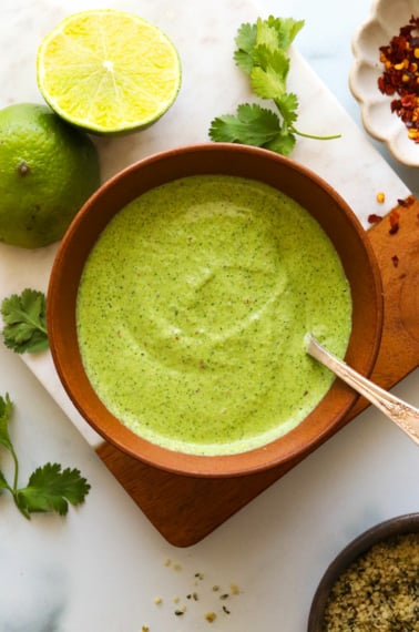 creamy cilantro sauce in a brown bowl with spoon.