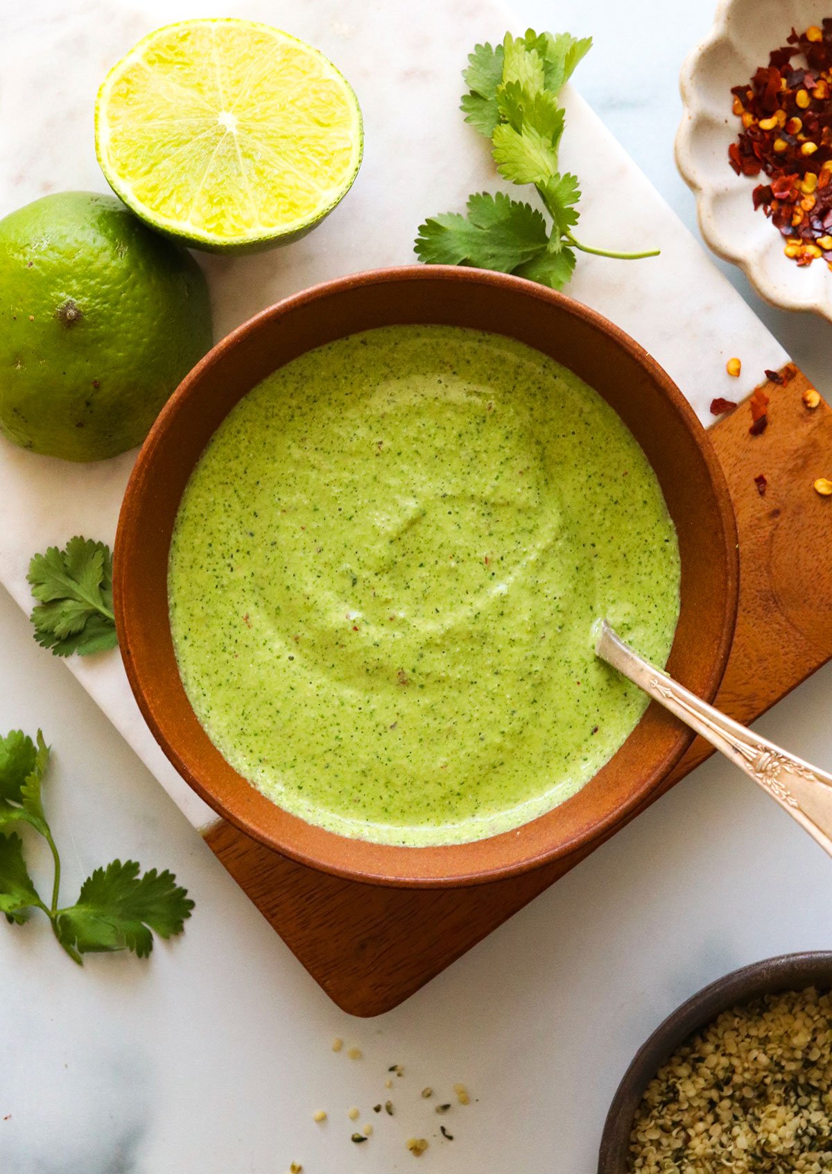 creamy cilantro sauce in a brown bowl with spoon.