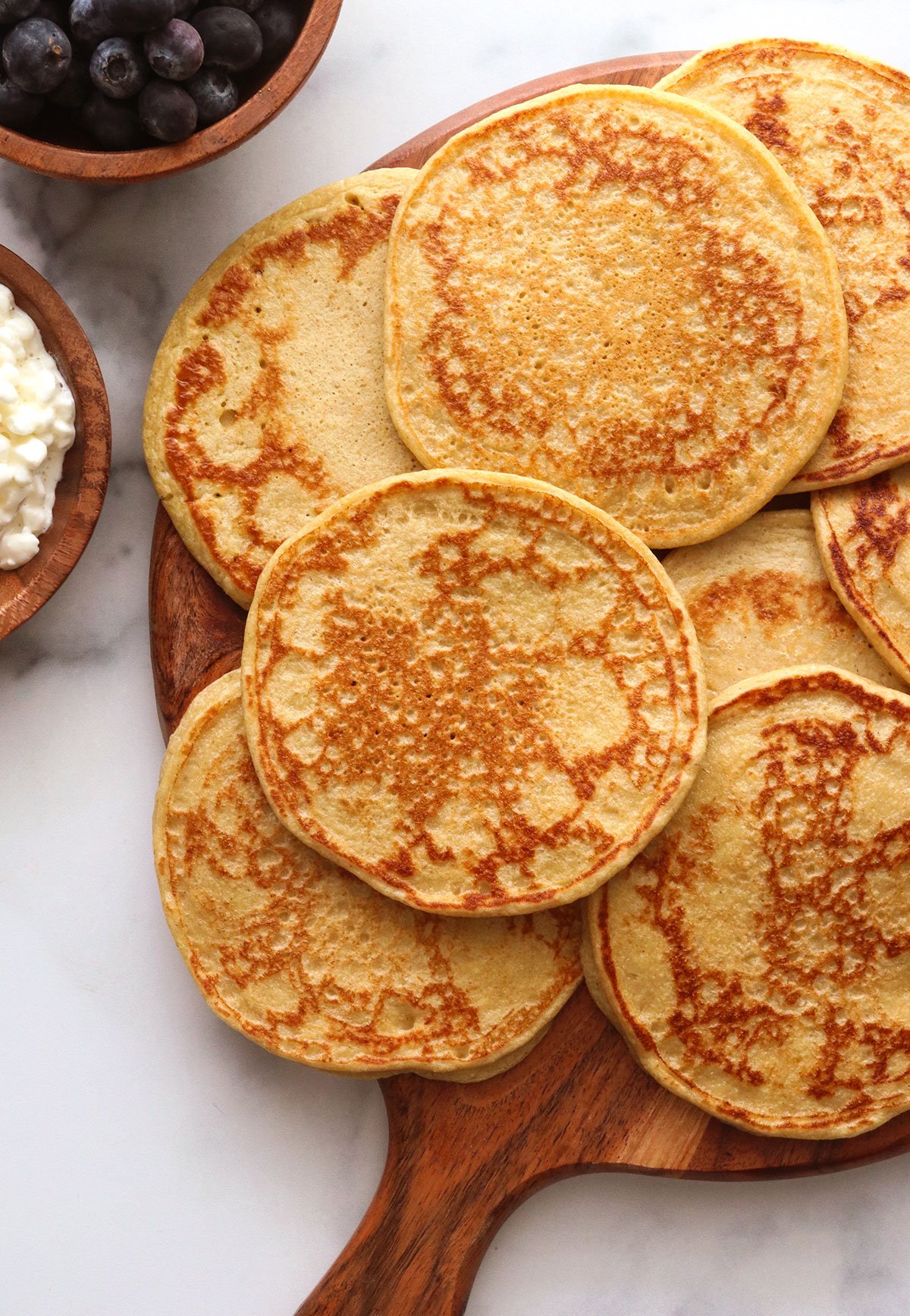 pancakes stacked on a wooden board.