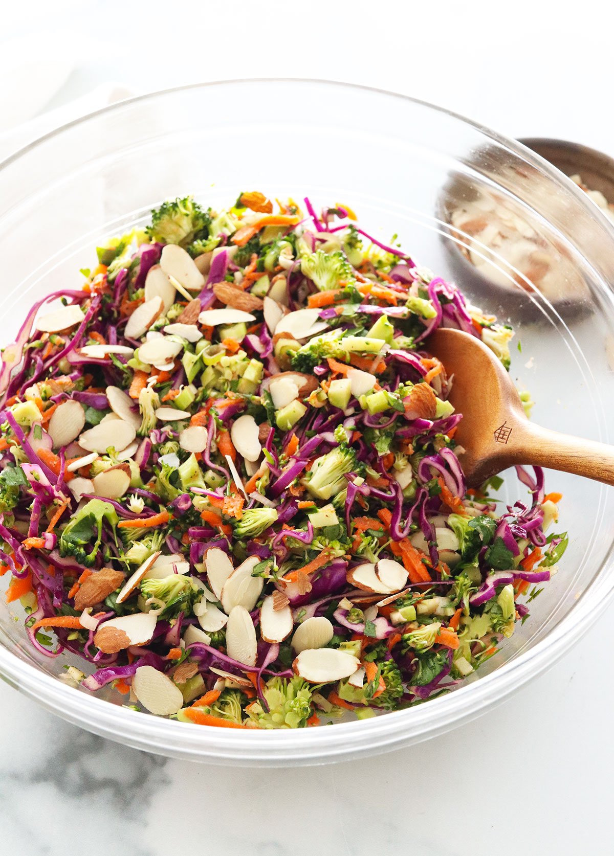 detox salad topped with sliced almonds in large glass bowl.