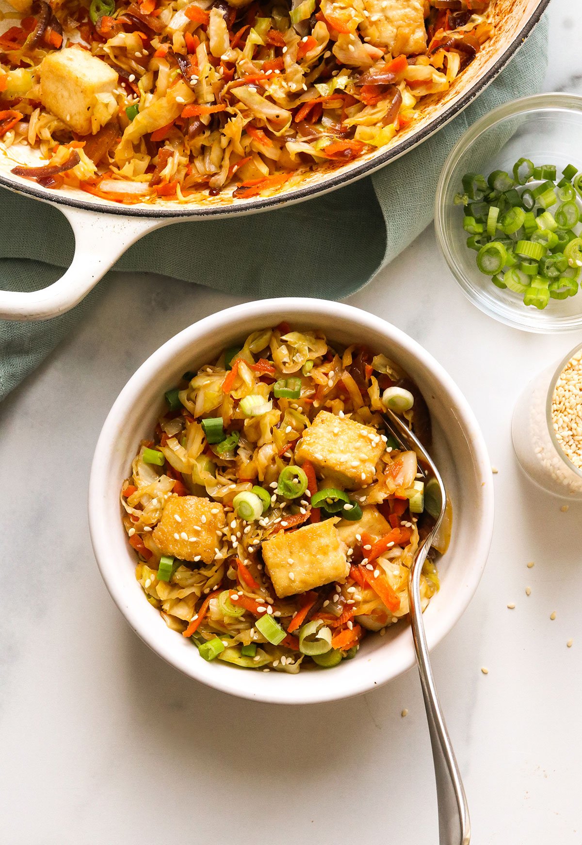 vegan egg roll in a bowl topped with tofu next to a skillet.