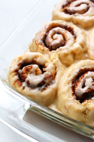 the best gluten-free cinnamon rolls in a glass pan topped with frosting.