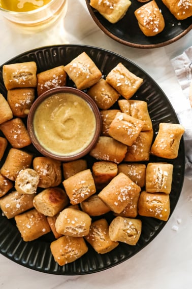 gluten-free pretzels on a black plate with honey mustard.