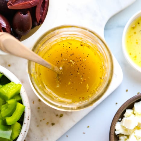 Homemade Greek dressing stirred in a glass jar.