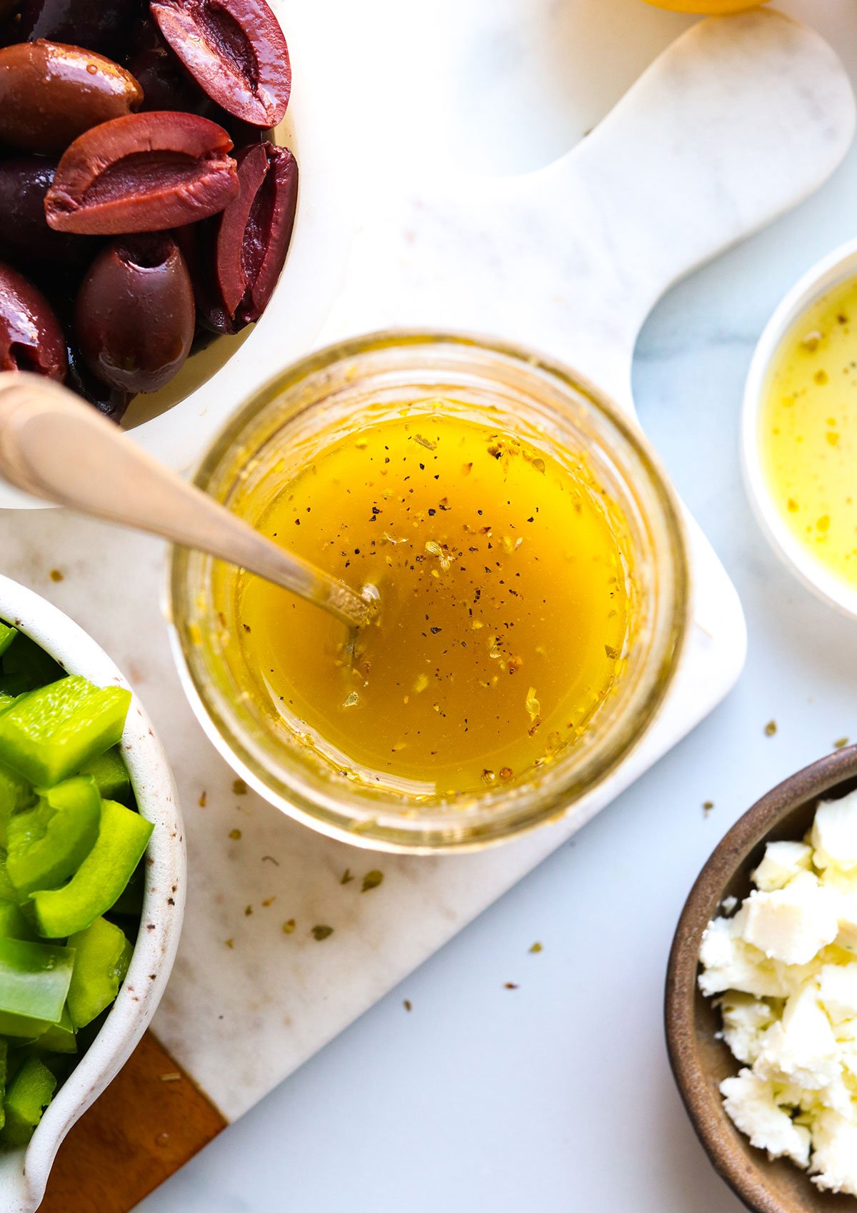 Homemade Greek dressing stirred in a glass jar.