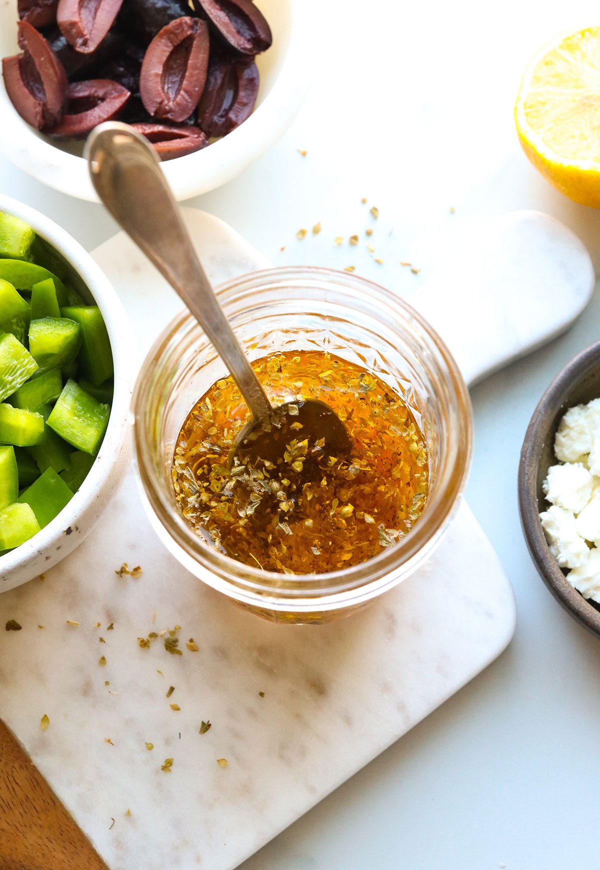 Greek dressing ingredients added to a glass jar.