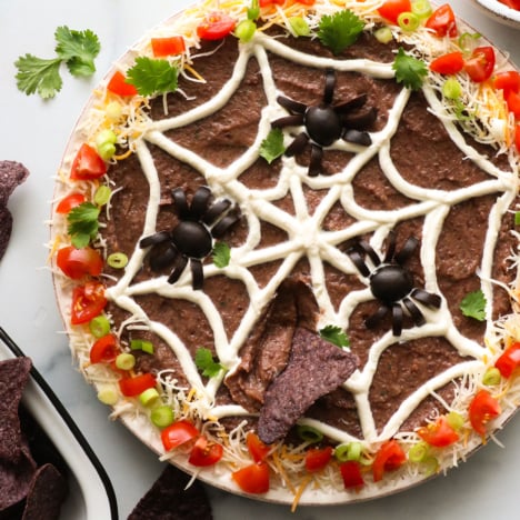 Halloween bean dip with spider web and olive spiders on top.