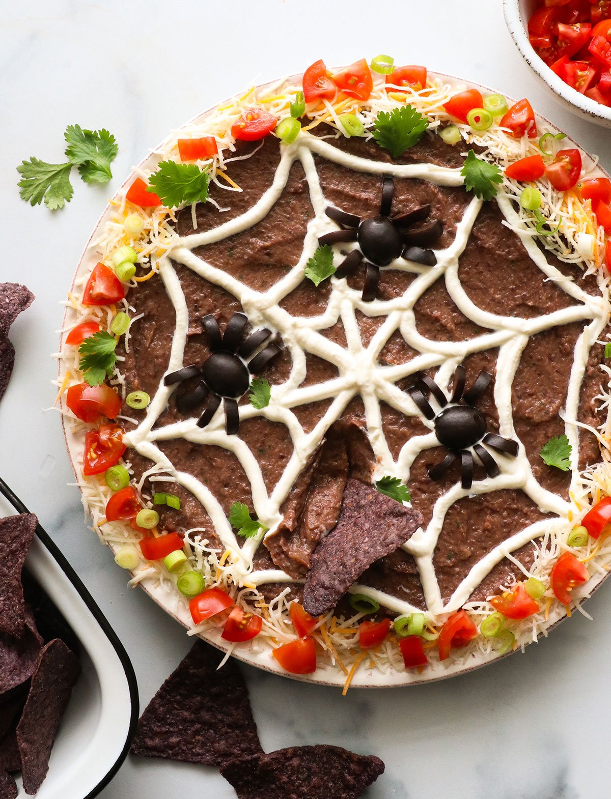 Halloween bean dip with spider web and olive spiders on top.