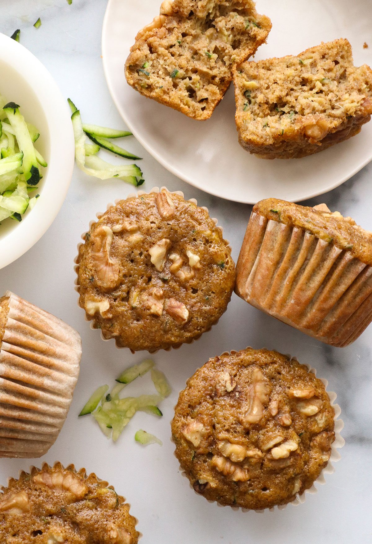 healthy zucchini muffins on a marble surface near shredded zucchini.