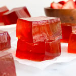 homemade jello squares stacked on parchment paper.