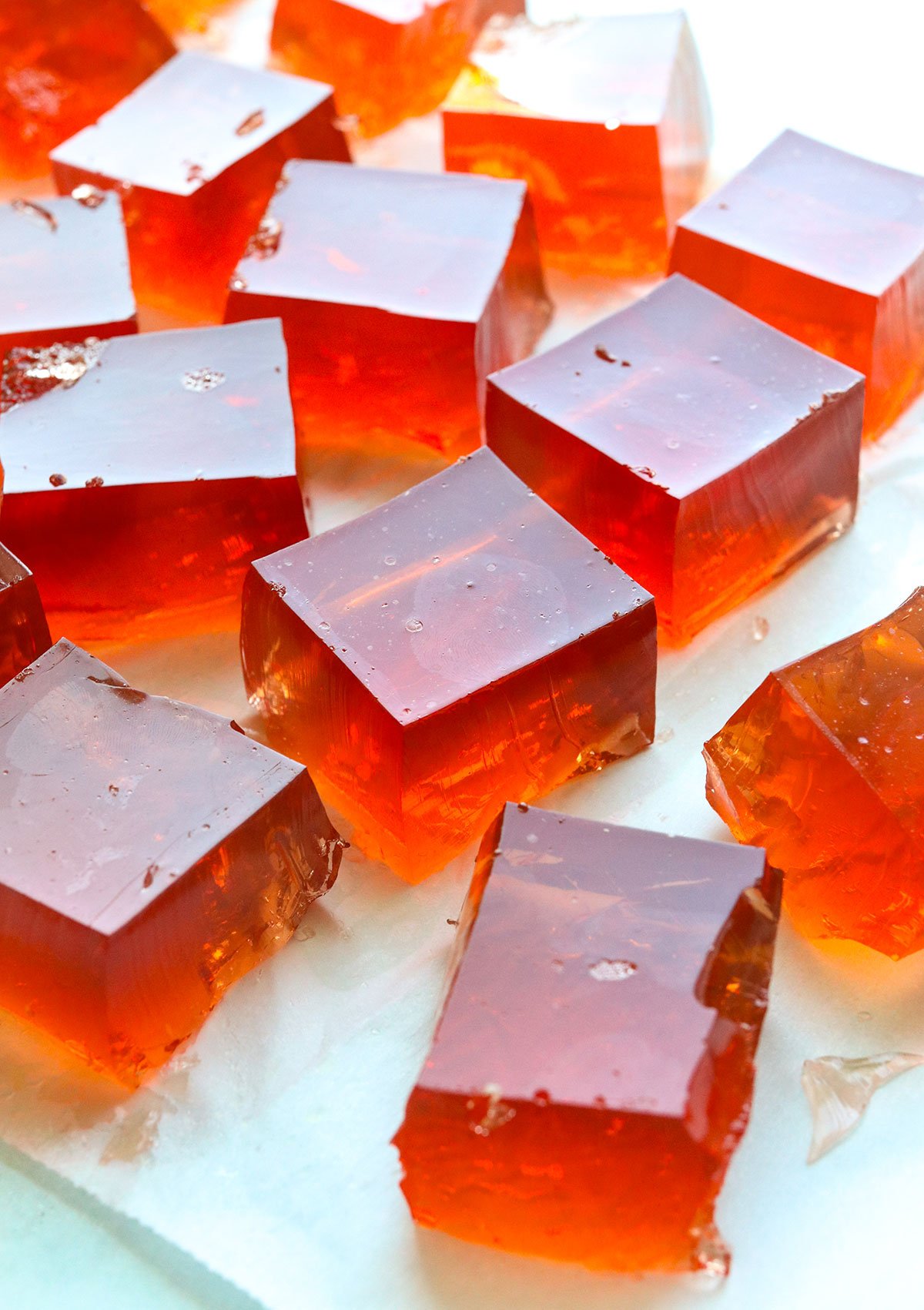 fruit juice jello sliced into squares on parchment paper.