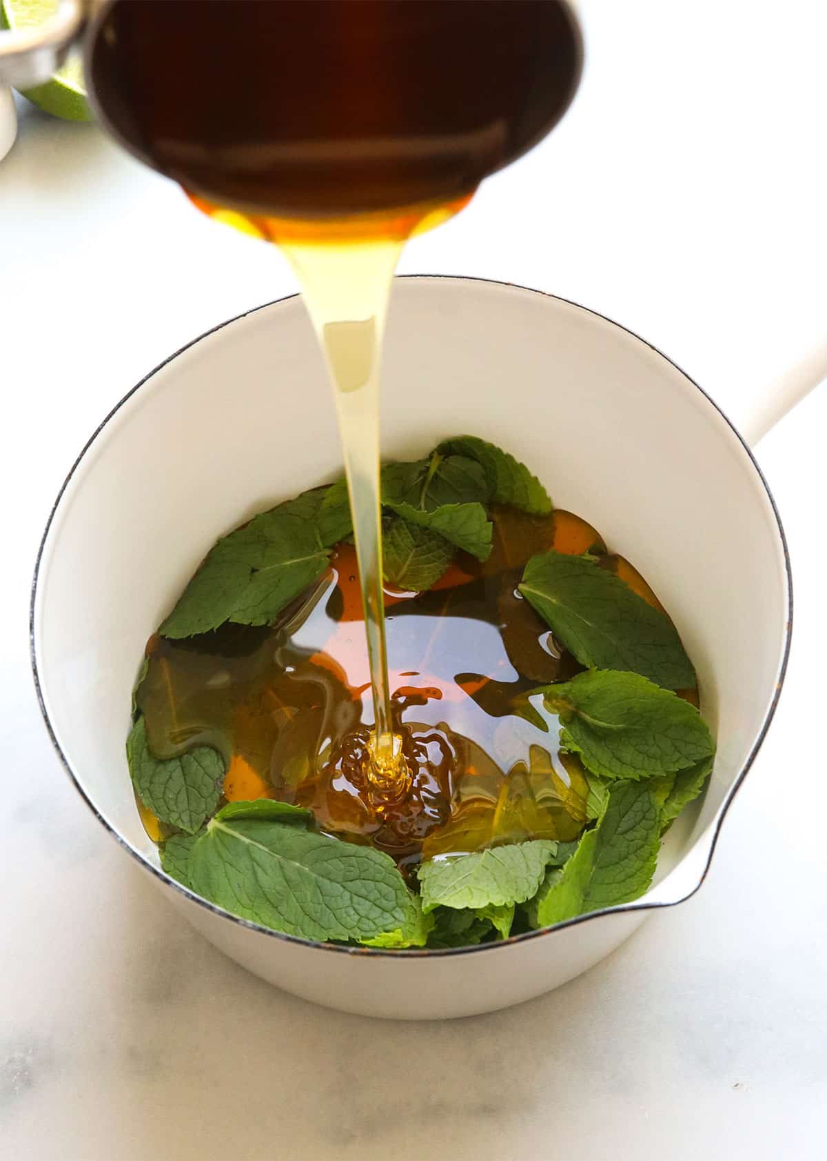 honey added to a small saucepan with mint leaves.