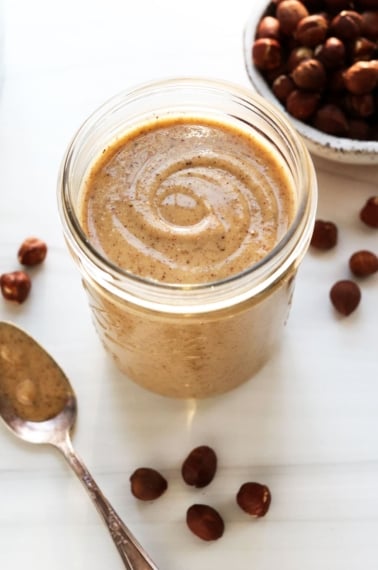 hazelnut butter in glass jar with spoon next to it.