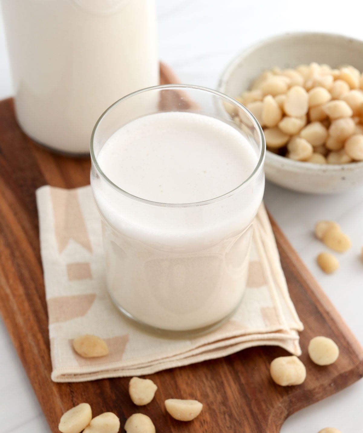 macadamia nut milk in glass with nuts around it