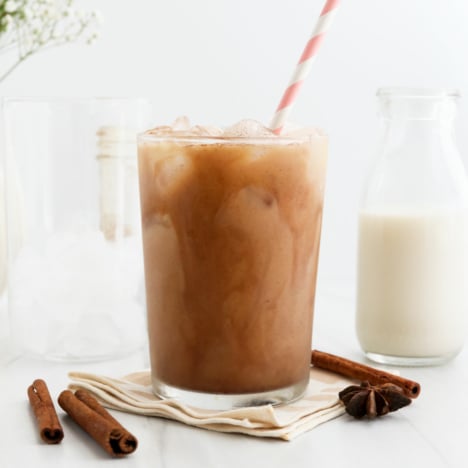 iced chai latte in a glass with a striped pink straw.