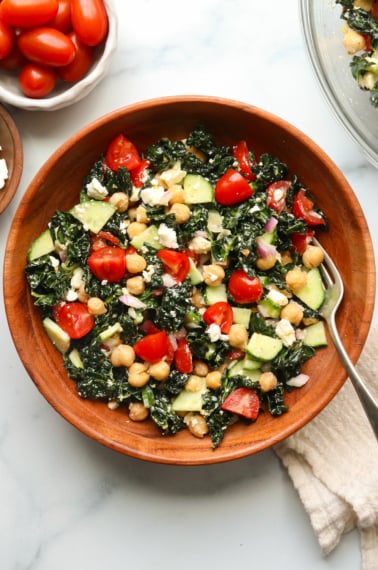 kale feta salad served in a wooden bowl with a fork.