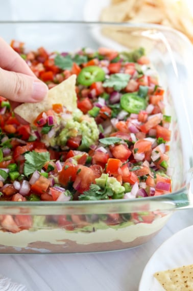 chip dipped into a dish of vegan 7 layer dip.