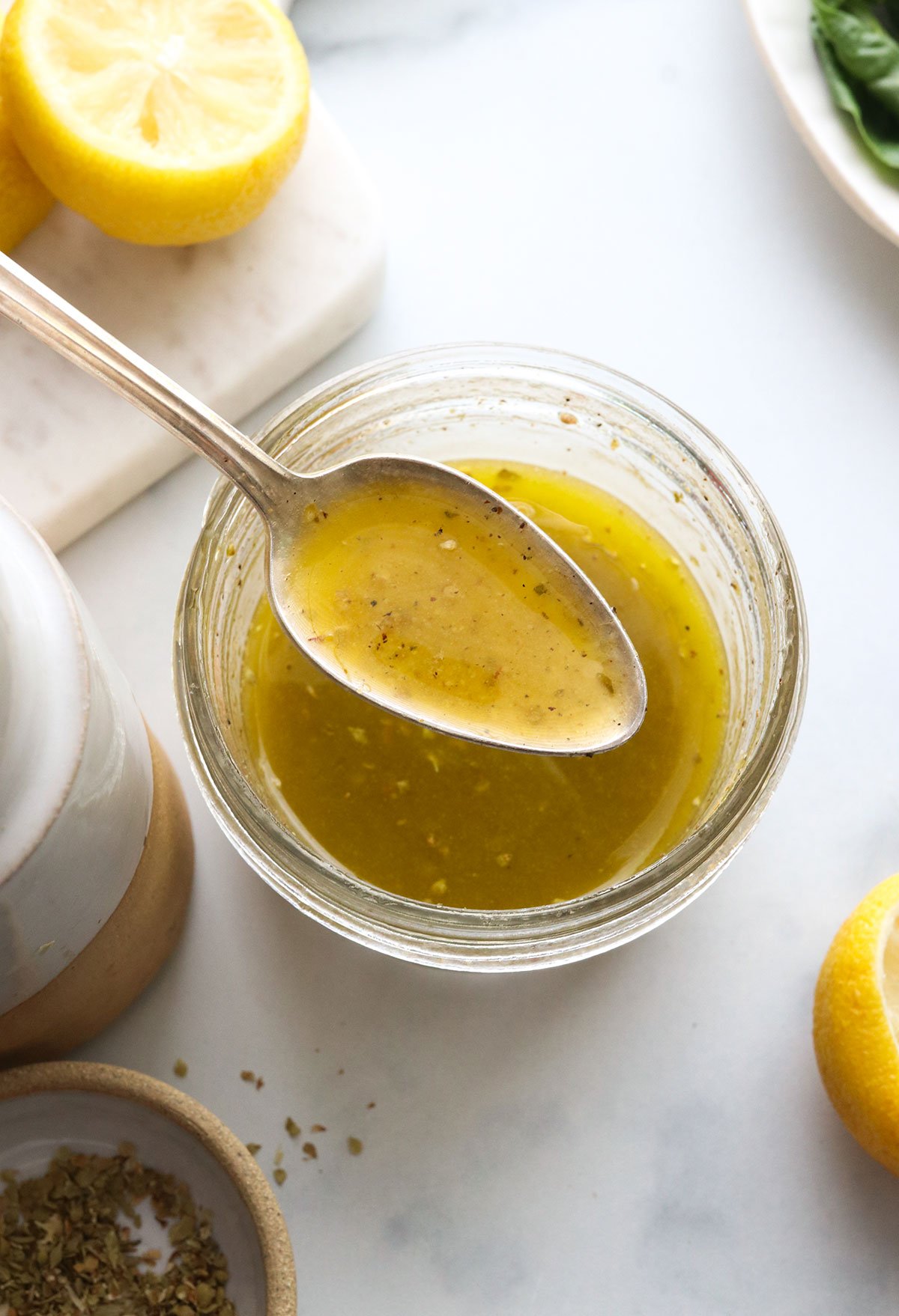 spoon lifted up with lemon vinaigrette over a jar.