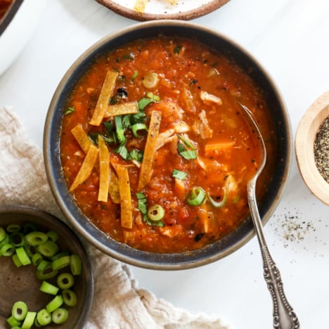 mexican chicken soup in bowl topped with tortilla strips.