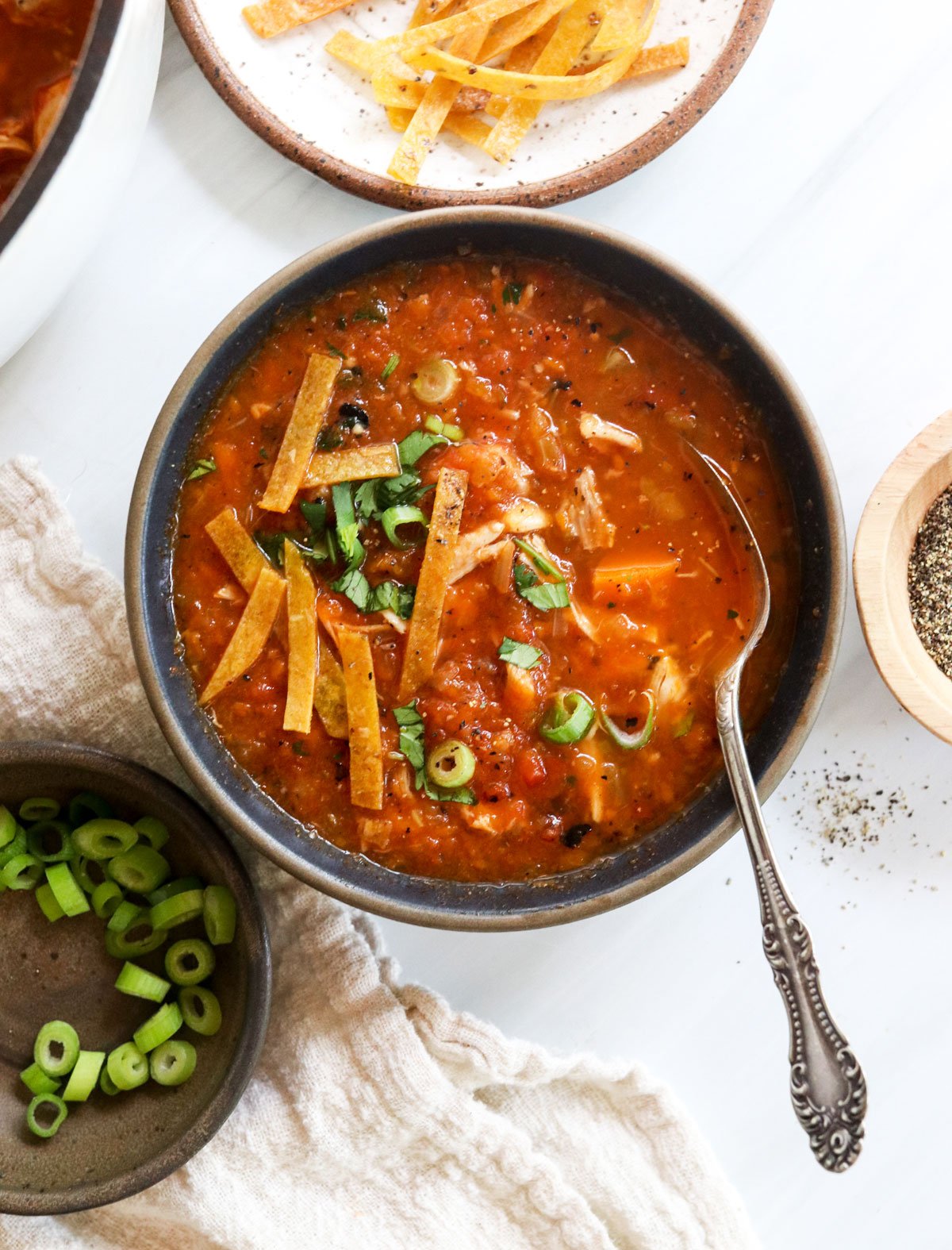 mexican chicken soup in bowl topped with tortilla strips.