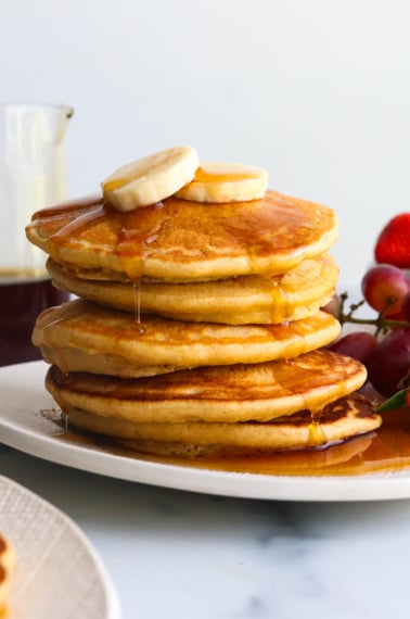 oat flour pancakes topped with banana slices and syrup.