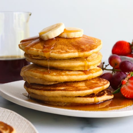 oat flour pancakes topped with banana slices and syrup.