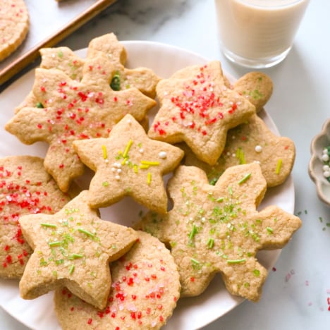 oat flour sugar cookies on a white plate topped with sprinkles.