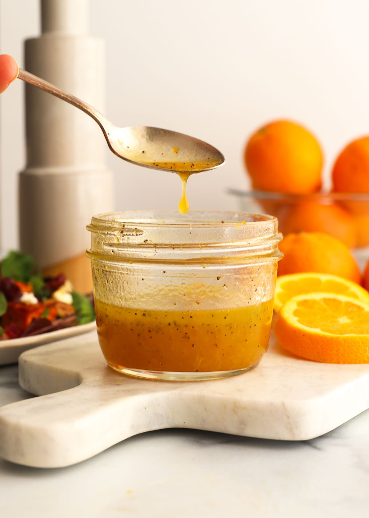 orange dressing dripping off a spoon into the jar.