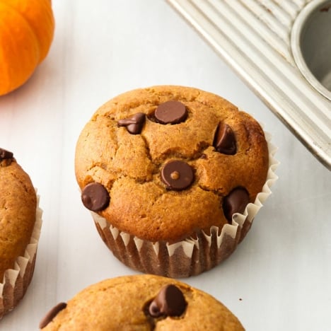 paleo pumpkin muffins cooling on a white surface.