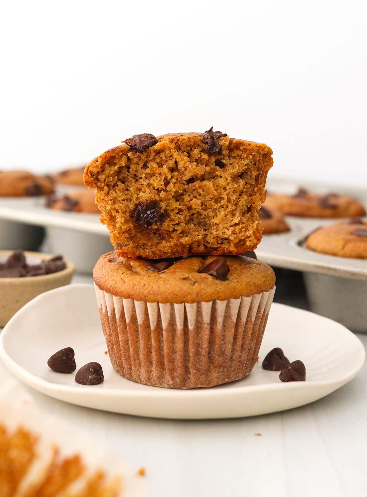 Paleo pumpkin muffins stacked on a white plate.